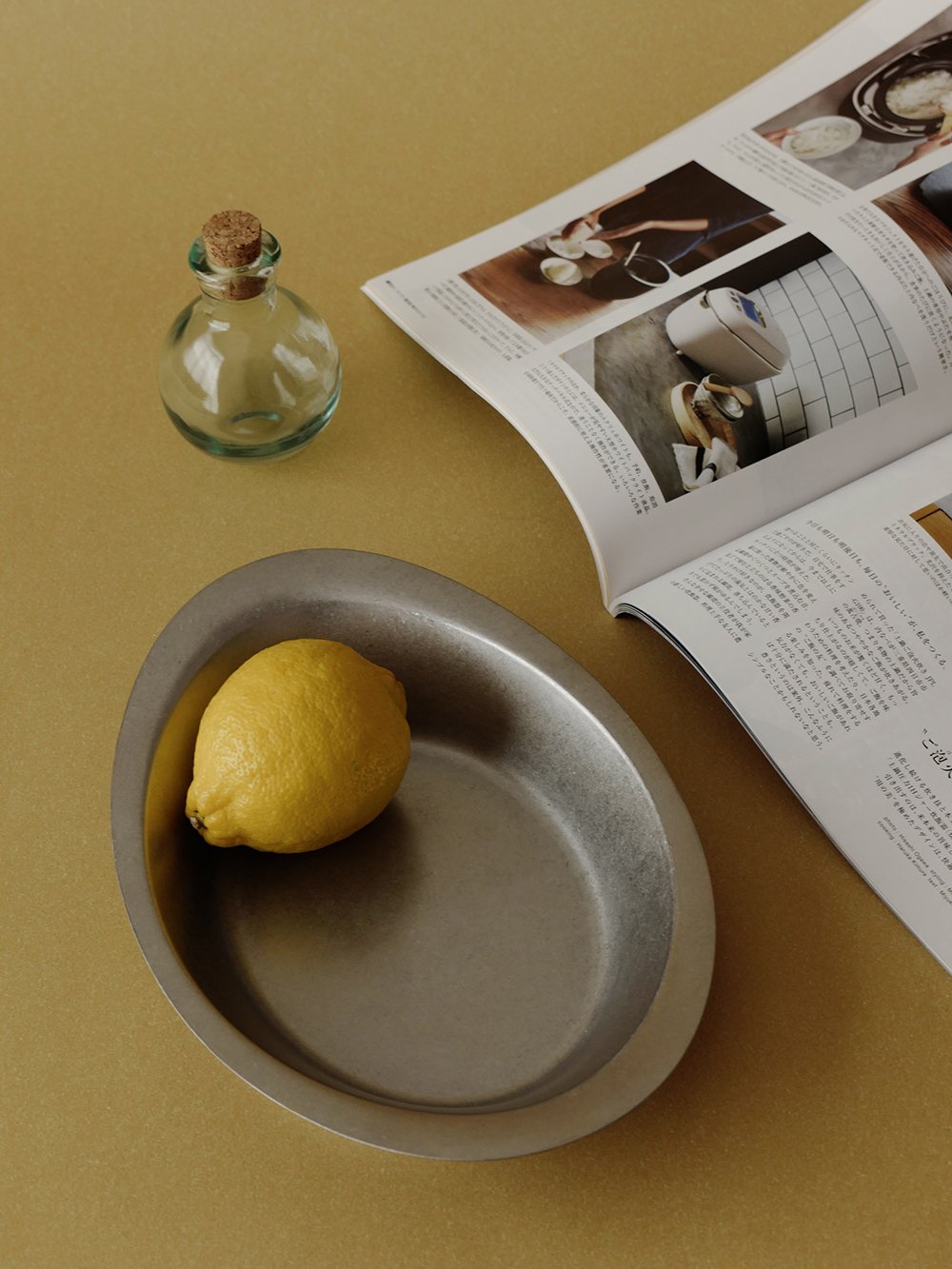 Ova plate with a lemon next to an open magazine
