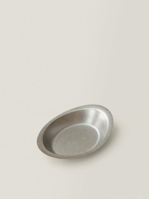 Ova oval stainless steel deep plate on a warm grey background